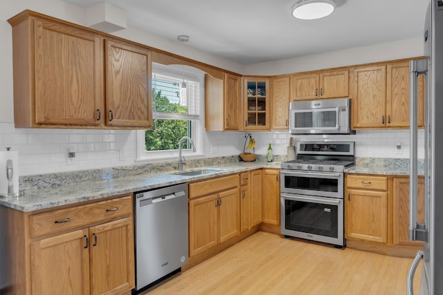 6 Goff Ave, Lewiston, ME 04240 - kitchen featuring appliances with stainless steel finishes, a sink, light wood finished floors, backsplash, and light stone countertops