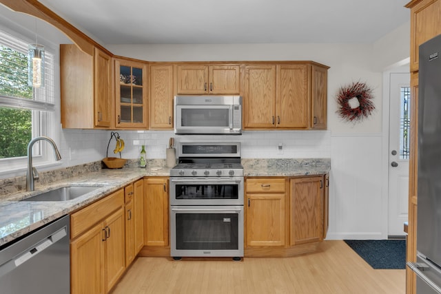 6 Goff Ave, Lewiston, ME 04240 - kitchen featuring appliances with stainless steel finishes, a sink, light wood-type flooring, glass insert cabinets, and decorative backsplash