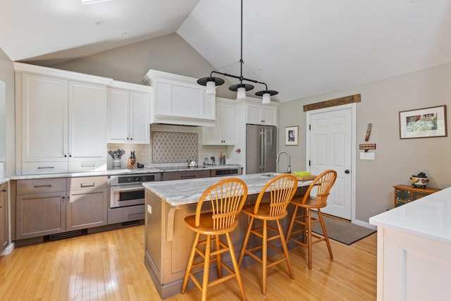 3 Blueberry Rd Unit 3, Yarmouth, ME 04096 - kitchen featuring appliances with stainless steel finishes, a sink, tasteful backsplash, light wood-style flooring, and a kitchen bar