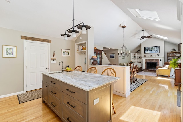 3 Blueberry Rd Unit 3, Yarmouth, ME 04096 - kitchen featuring a sink, a brick fireplace, light wood finished floors, a chandelier, and a skylight