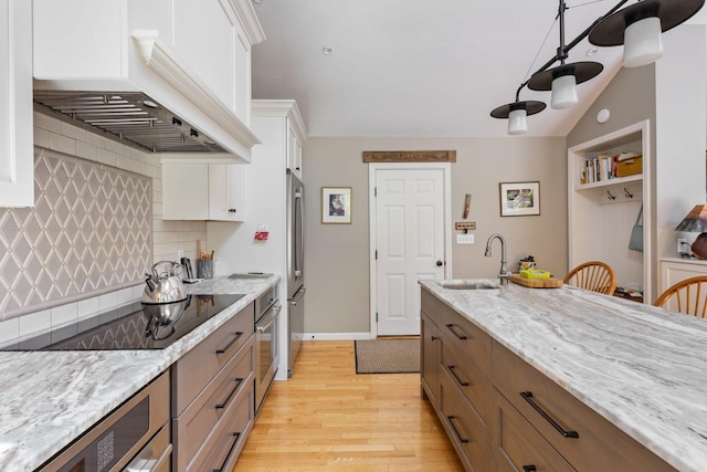 3 Blueberry Rd Unit 3, Yarmouth, ME 04096 - kitchen featuring a sink, custom exhaust hood, light wood-style flooring, decorative backsplash, and white cabinets