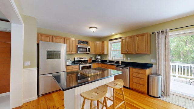 471 Owls Nest Rd, Shapleigh, ME 04076 - kitchen featuring appliances with stainless steel finishes, light wood finished floors, a sink, a breakfast bar, and dark countertops
