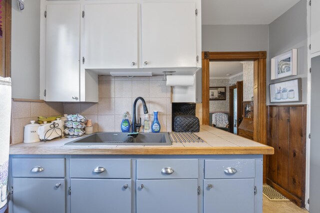 94 Union St, Bath, ME 04530 - kitchen with a sink, decorative backsplash, white cabinets, and crown molding