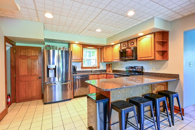 24 Western Ave, Auburn, ME 04210 - kitchen with stainless steel appliances, a sink, a peninsula, dark stone counters, and light tile patterned flooring