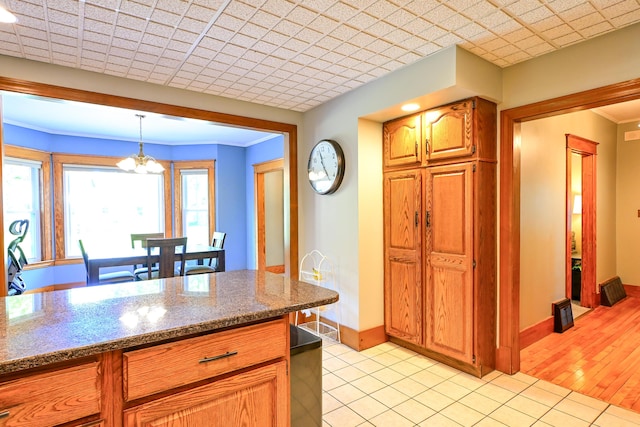 24 Western Ave, Auburn, ME 04210 - kitchen featuring baseboards, a chandelier, decorative light fixtures, brown cabinets, and dark stone countertops