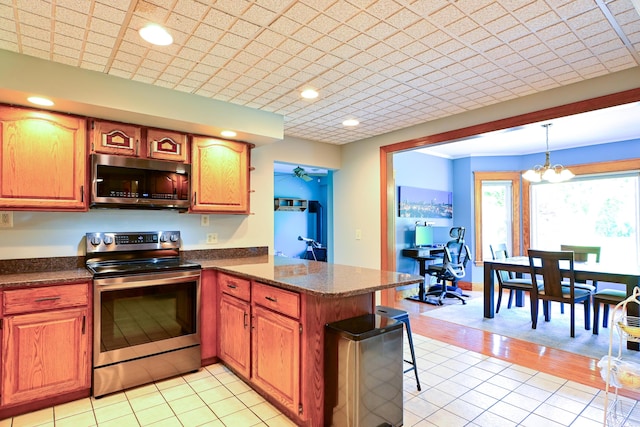 24 Western Ave, Auburn, ME 04210 - kitchen with appliances with stainless steel finishes, a peninsula, a chandelier, light tile patterned floors, and pendant lighting