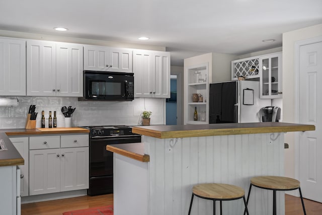 27 Russell Ln, Damariscotta, ME 04543 - kitchen with black appliances, a kitchen bar, light wood finished floors, decorative backsplash, and recessed lighting