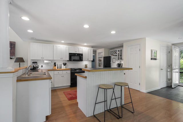 27 Russell Ln, Damariscotta, ME 04543 - kitchen with black appliances, a breakfast bar area, white cabinets, tasteful backsplash, and dark wood finished floors
