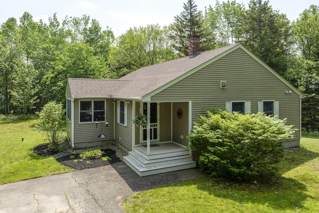 27 Russell Ln, Damariscotta, ME 04543 - view of front of house with a chimney, a front lawn, a shingled roof, and asphalt driveway