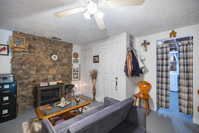 76 Punkintown Rd, Eliot, ME 03903 - living room with a textured ceiling, a ceiling fan, a stone fireplace, and washer / dryer