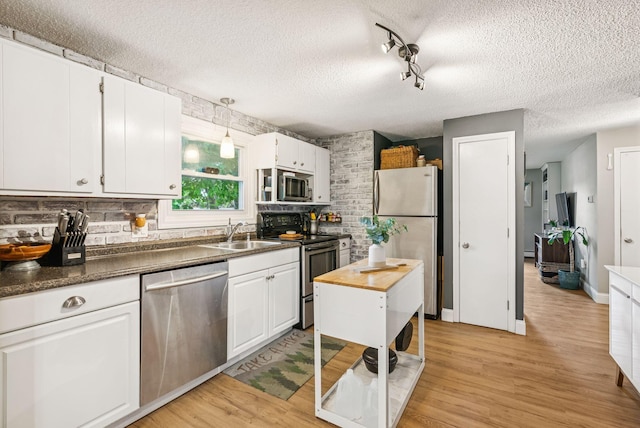 11 Meadow Ln, Portland, ME 04103 - kitchen with appliances with stainless steel finishes, a sink, a textured ceiling, white cabinets, and backsplash