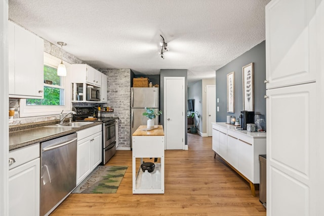 11 Meadow Ln, Portland, ME 04103 - kitchen with appliances with stainless steel finishes, a sink, white cabinets, a textured ceiling, and light wood-type flooring