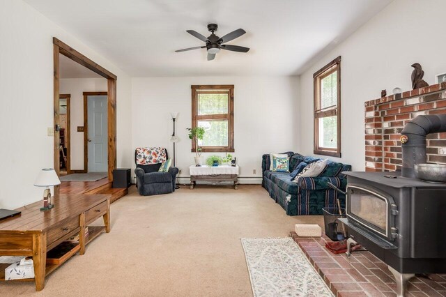 44 Pine Meadow Ct, North Berwick, ME 03906 - carpeted living area with a wood stove, a ceiling fan, a baseboard heating unit, and a baseboard radiator