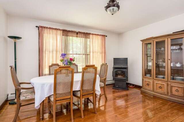 44 Pine Meadow Ct, North Berwick, ME 03906 - dining room with a wood stove, wood finished floors, a baseboard radiator, and a baseboard heating unit