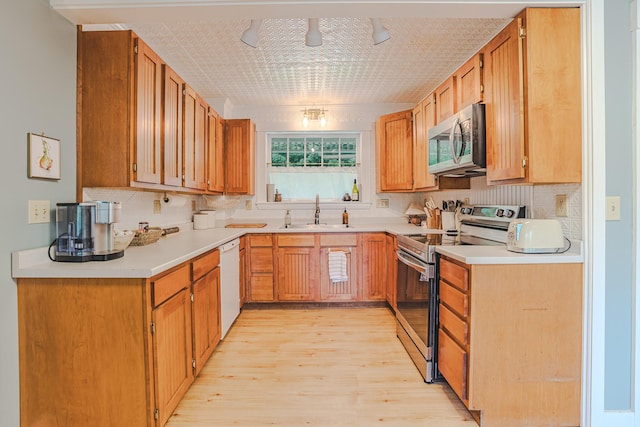 24 High St, Livermore Falls, ME 04254 - kitchen featuring appliances with stainless steel finishes, light wood-style flooring, decorative backsplash, and light countertops