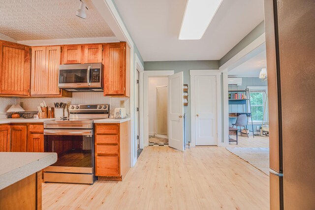 24 High St, Livermore Falls, ME 04254 - kitchen with appliances with stainless steel finishes, light wood finished floors, light countertops, and a wall mounted air conditioner
