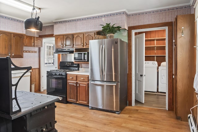 785 W Main St, Waldoboro, ME 04572 - kitchen featuring stainless steel appliances, washer and clothes dryer, under cabinet range hood, wallpapered walls, and brown cabinetry