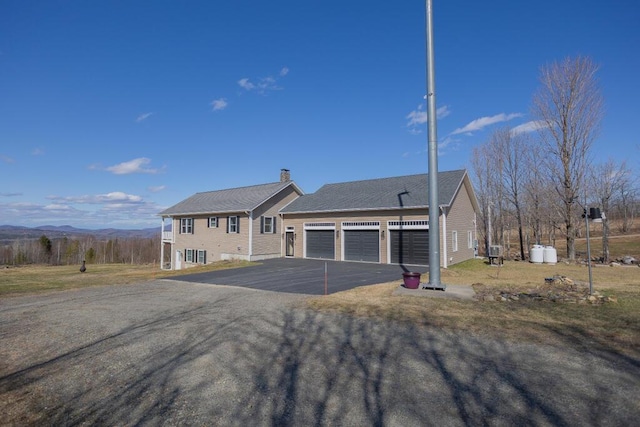 135 Lyle Hall Rd, Wilton, ME 04294 - view of front of property with a chimney, asphalt driveway, a mountain view, and an attached garage