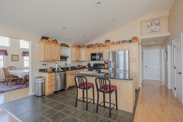 135 Lyle Hall Rd, Wilton, ME 04294 - kitchen featuring black appliances, light brown cabinetry, vaulted ceiling, a breakfast bar area, and a center island