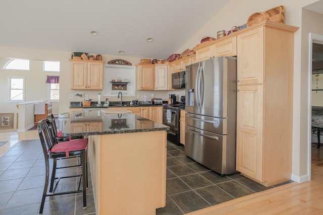 135 Lyle Hall Rd, Wilton, ME 04294 - kitchen featuring black appliances, light brown cabinetry, a sink, a center island, and a breakfast bar area