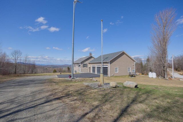 135 Lyle Hall Rd, Wilton, ME 04294 - rear view of house with driveway, a garage, a lawn, and a chimney