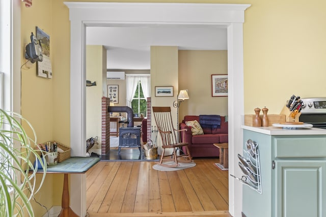 145 Pork Point Rd, Bowdoinham, ME 04008 - living area with a wood stove, a wall mounted AC, and light wood finished floors