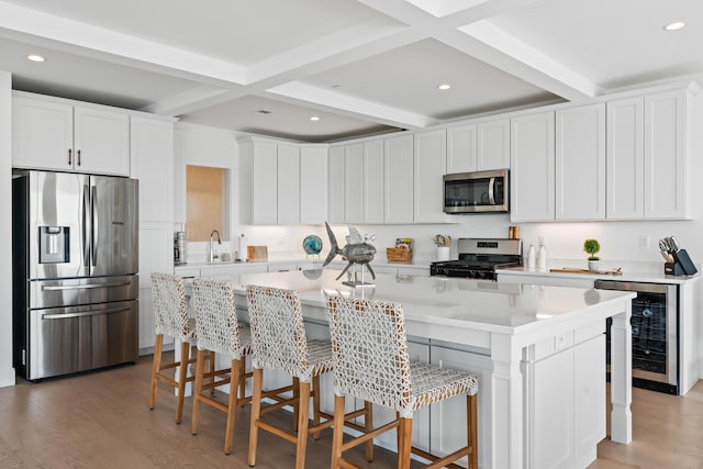 218 Washington Ave Unit 401, Portland, ME 04101 - kitchen with appliances with stainless steel finishes, wine cooler, beam ceiling, light countertops, and a kitchen breakfast bar