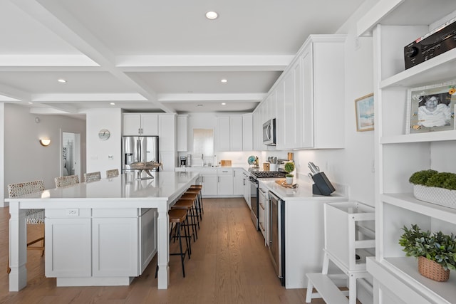 218 Washington Ave Unit 401, Portland, ME 04101 - kitchen with appliances with stainless steel finishes, a kitchen bar, beamed ceiling, white cabinetry, and recessed lighting
