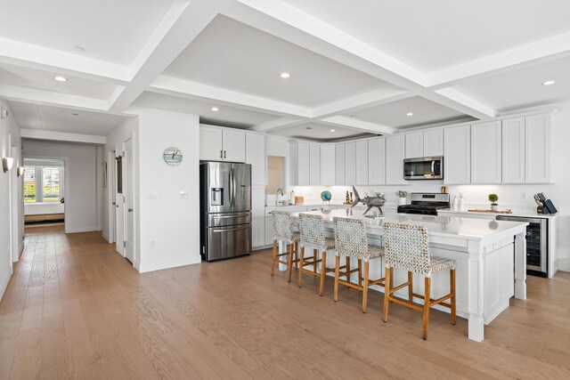 218 Washington Ave Unit 401, Portland, ME 04101 - kitchen with appliances with stainless steel finishes, wine cooler, coffered ceiling, a breakfast bar area, and light countertops