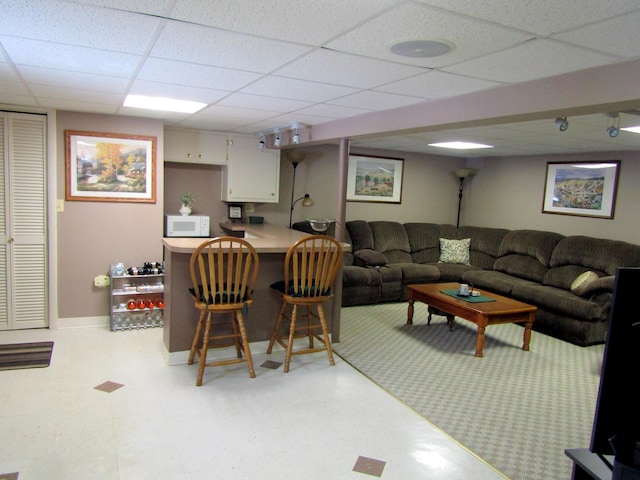 369 Grove St, Lewiston, ME 04240 - living area featuring a drop ceiling, light flooring, a bar, and baseboards