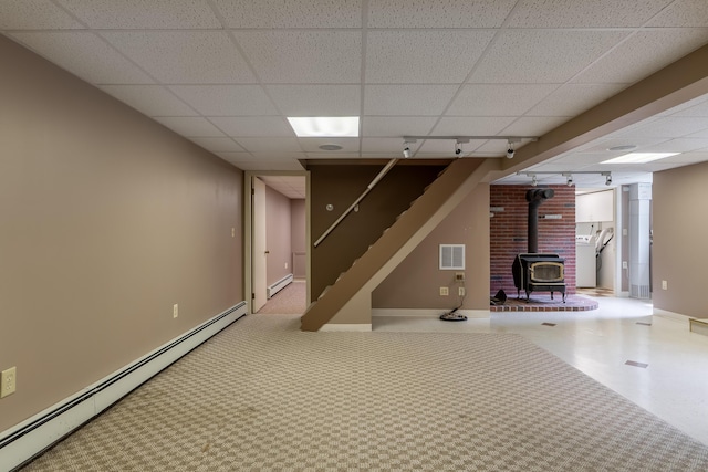 369 Grove St, Lewiston, ME 04240 - below grade area with a wood stove, a baseboard radiator, a drop ceiling, washer / dryer, and stairway