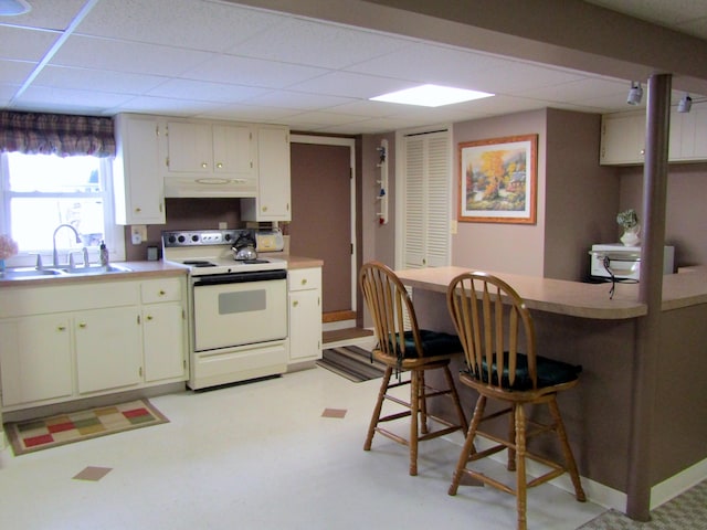 369 Grove St, Lewiston, ME 04240 - kitchen featuring white electric range, under cabinet range hood, a sink, a drop ceiling, and a kitchen bar