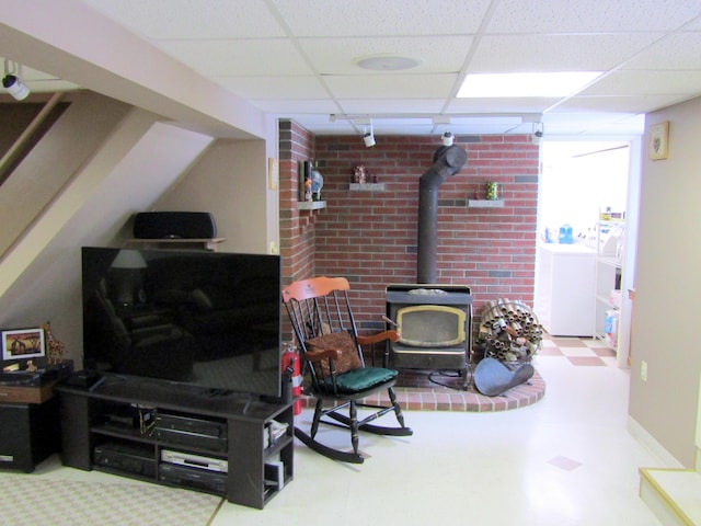 369 Grove St, Lewiston, ME 04240 - living room featuring a wood stove, washing machine and dryer, a paneled ceiling, tile patterned floors, and baseboards