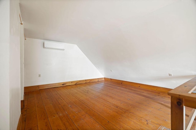 427 Haley Rd, Kittery, ME 03905 - empty room with an AC wall unit, lofted ceiling, hardwood / wood-style floors, and baseboards