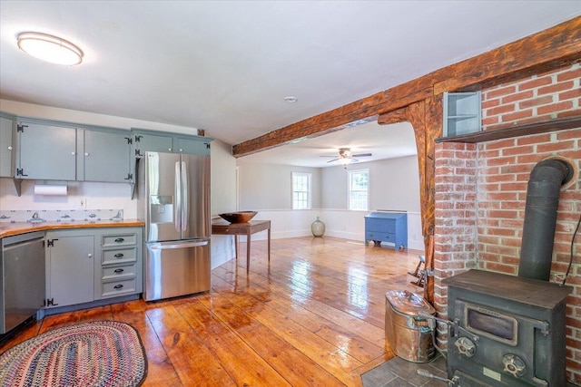 15 Feylers Corner Rd, Waldoboro, ME 04572 - kitchen with appliances with stainless steel finishes, a ceiling fan, light wood-style flooring, a wood stove, and beam ceiling