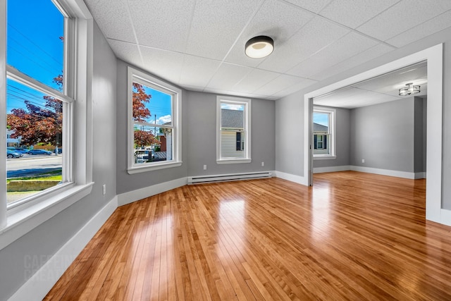 181 Webster St, Lewiston, ME 04240 - unfurnished room featuring baseboard heating, light wood-style floors, a drop ceiling, and baseboards