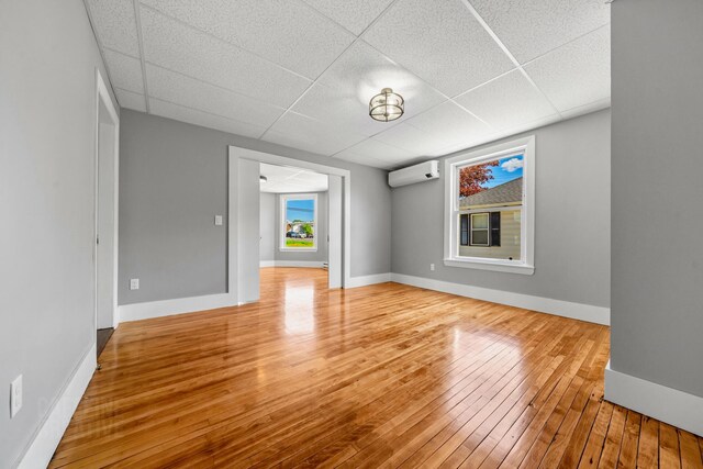 181 Webster St, Lewiston, ME 04240 - empty room with a drop ceiling, a wall unit AC, wood-type flooring, and baseboards