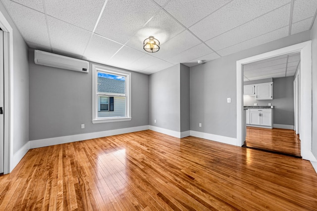 181 Webster St, Lewiston, ME 04240 - spare room with a wall mounted air conditioner, a drop ceiling, light wood-style floors, and baseboards