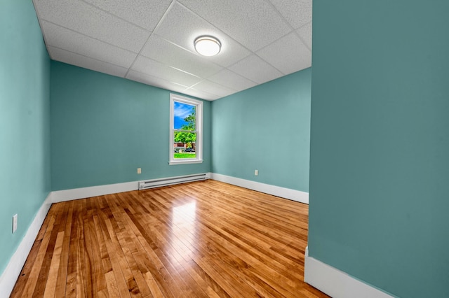 181 Webster St, Lewiston, ME 04240 - unfurnished room with a baseboard heating unit, hardwood / wood-style floors, baseboards, and a drop ceiling