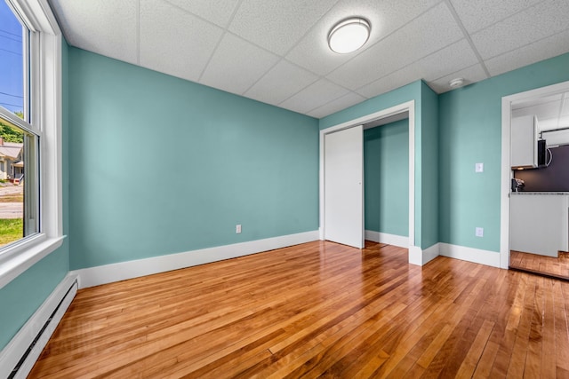 181 Webster St, Lewiston, ME 04240 - unfurnished bedroom featuring a baseboard radiator, multiple windows, hardwood / wood-style floors, a closet, and a drop ceiling