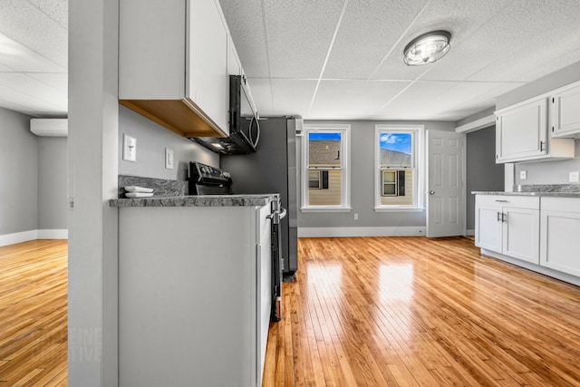 181 Webster St, Lewiston, ME 04240 - kitchen featuring light wood-style flooring, a drop ceiling, baseboards, stainless steel microwave, and white cabinets