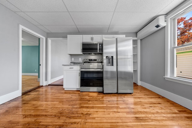 181 Webster St, Lewiston, ME 04240 - kitchen with appliances with stainless steel finishes, light wood finished floors, white cabinets, a paneled ceiling, and baseboards