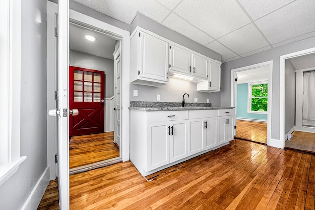 181 Webster St, Lewiston, ME 04240 - kitchen with light wood-type flooring, a sink, white cabinets, light stone counters, and baseboards