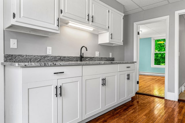 181 Webster St, Lewiston, ME 04240 - kitchen featuring a baseboard radiator, dark wood-style floors, white cabinets, a sink, and stone counters