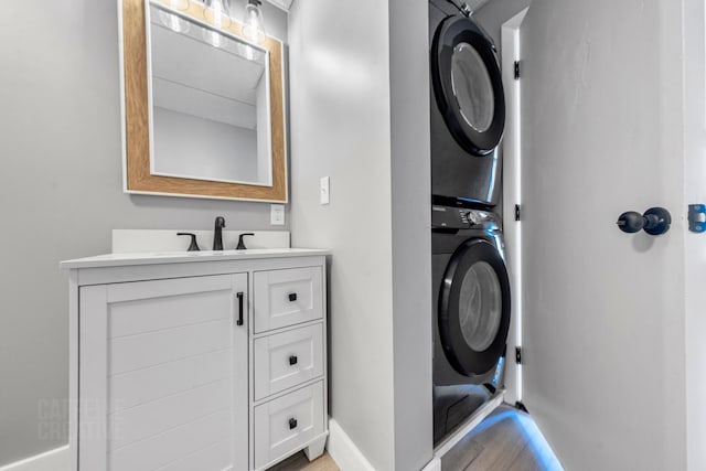 181 Webster St, Lewiston, ME 04240 - laundry room with stacked washing machine and dryer, a sink, light wood-style floors, and baseboards