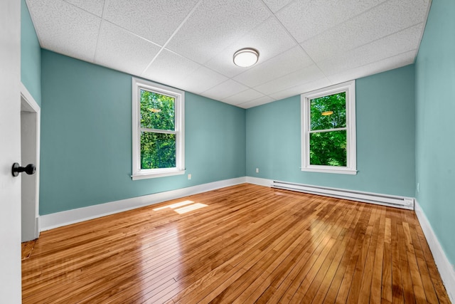 181 Webster St, Lewiston, ME 04240 - empty room with a baseboard radiator, hardwood / wood-style floors, baseboards, and a drop ceiling