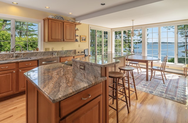 4 Roland Kimball Rd Unit 2, Freeport, ME 04032 - kitchen featuring brown cabinets, a kitchen breakfast bar, light wood-style floors, a kitchen island, and dark stone counters