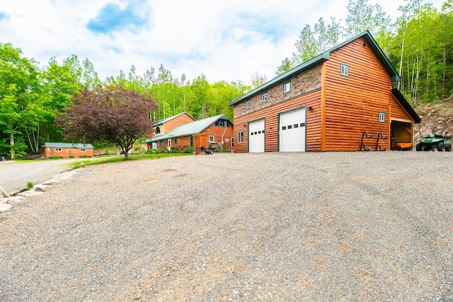 15 Doe Cir, Bingham, ME 04920 - view of home's exterior with faux log siding, driveway, and a detached garage