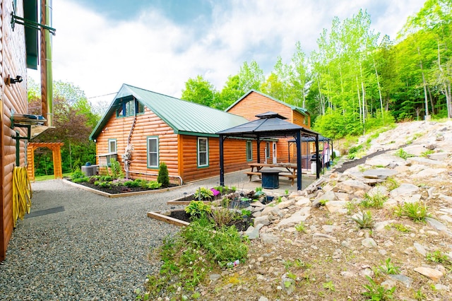15 Doe Cir, Bingham, ME 04920 - view of front of home with a gazebo, faux log siding, a patio, metal roof, and central AC