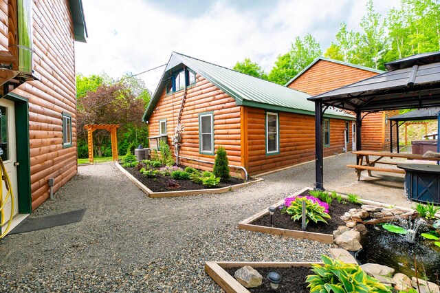 15 Doe Cir, Bingham, ME 04920 - view of side of home with a gazebo, a patio, faux log siding, metal roof, and central AC